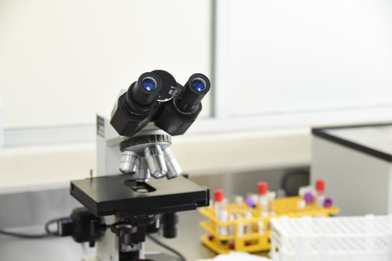 about-bg A close-up of a laboratory microscope with test tubes in a scientific research facility.